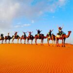 Group of tourists from Spain riding camels in Merzouga Dunes